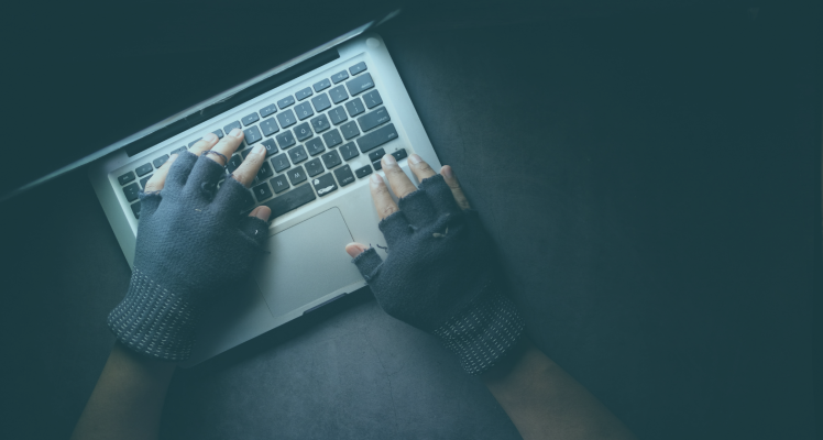 A mans hands in gloves typing on a keyboard